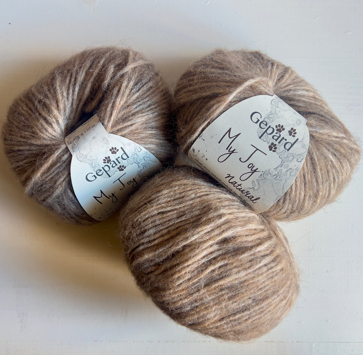 Three balls of Gepard My Joy yarn in 146 Stone Moss, a muted taupe shade
