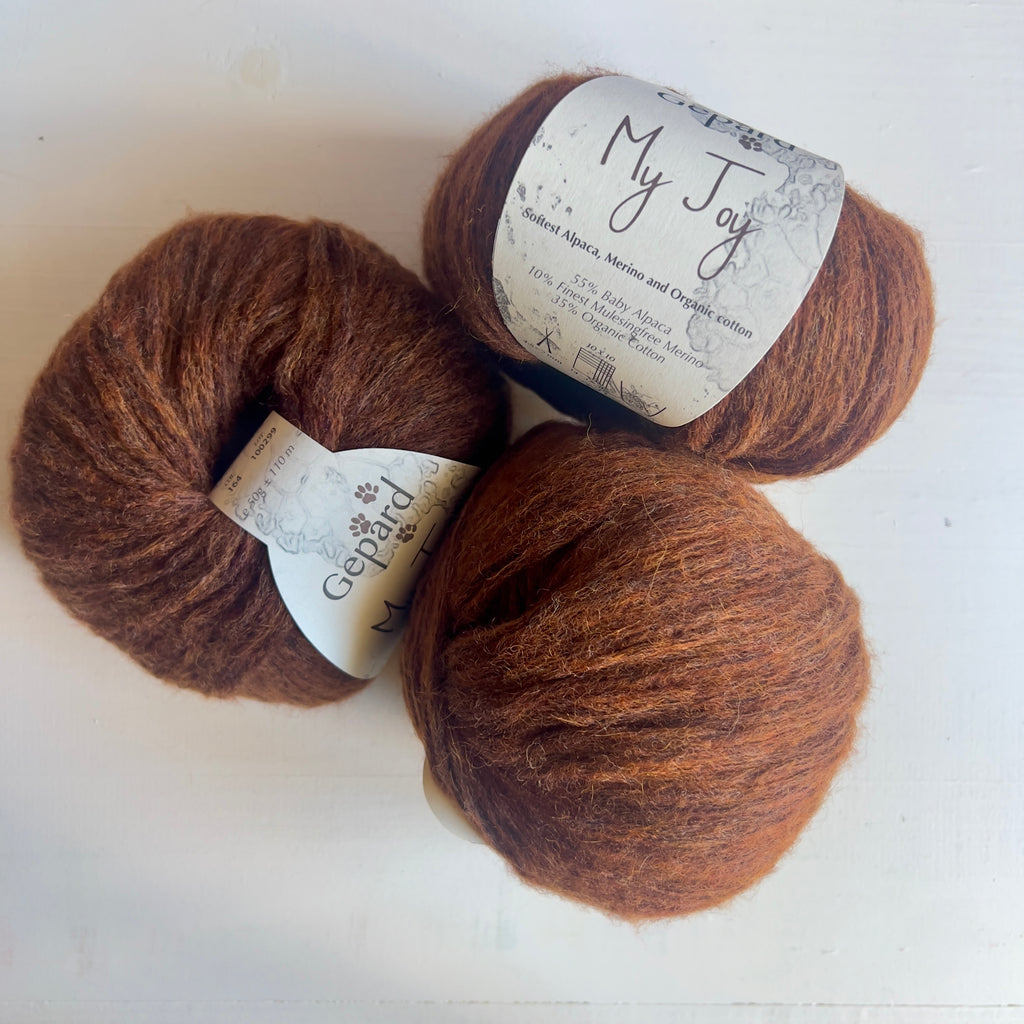 Three balls of Gepard My Joy yarn in 164 Copper Fleece, a warm copper-brown shade