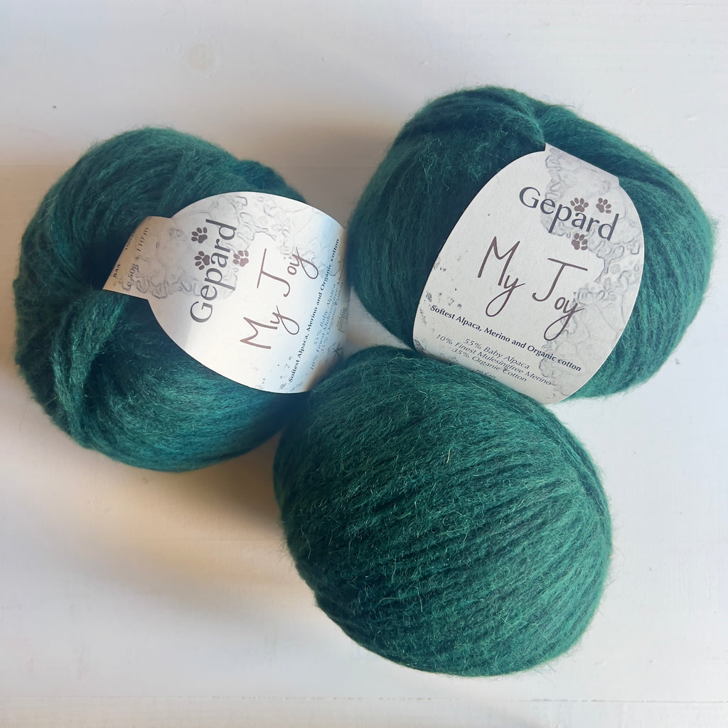 Three balls of Gepard My Joy yarn in 844 Emerald Deep, a rich green shade